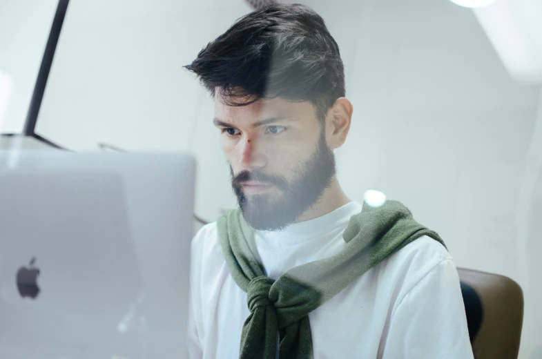 a man in green scarf holding up a white laptop