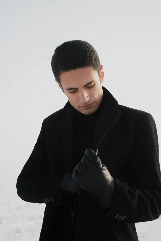 a man wearing a black coat standing in the snow