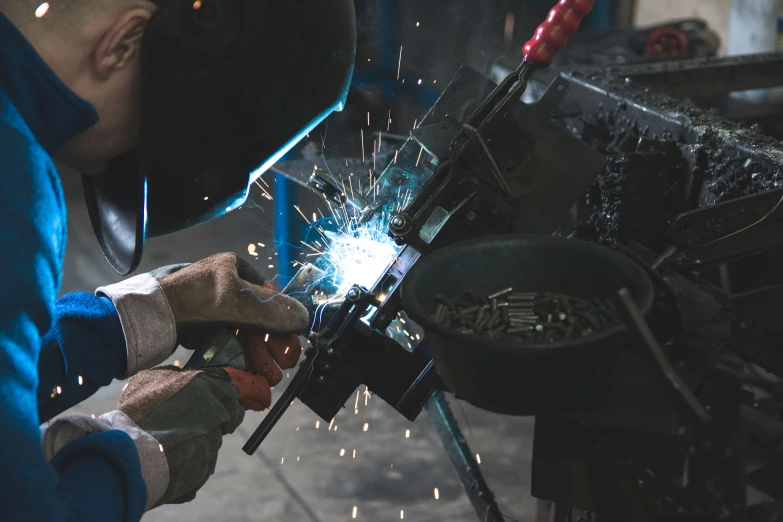 a welder welding and grinding a piece with a grinder