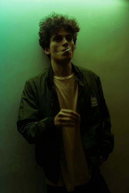 a young man smoking while wearing a green jacket