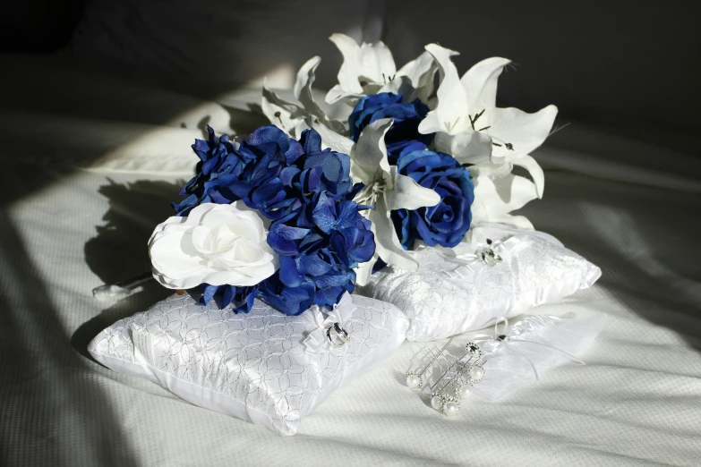 two bouquets of flowers are on the edge of an unmade bed