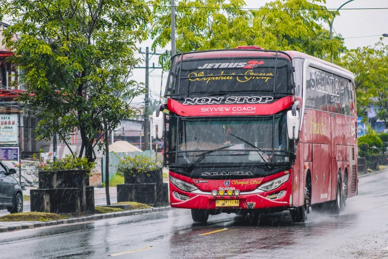 a red double decker bus driving down a rain soaked street