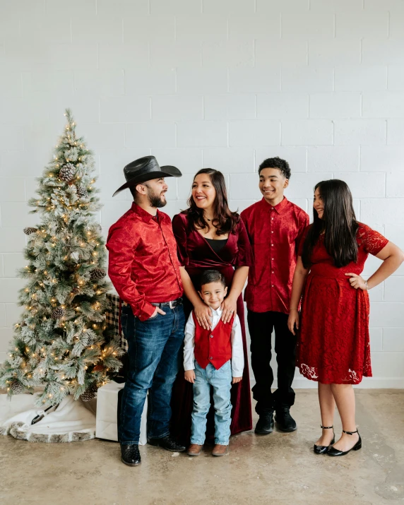 a family poses in front of a christmas tree