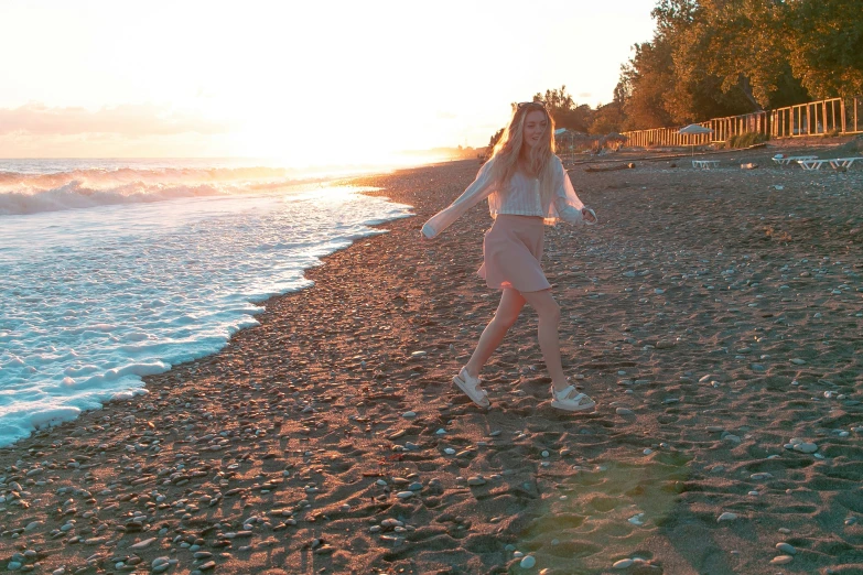 girl walking on the beach in front of the sun