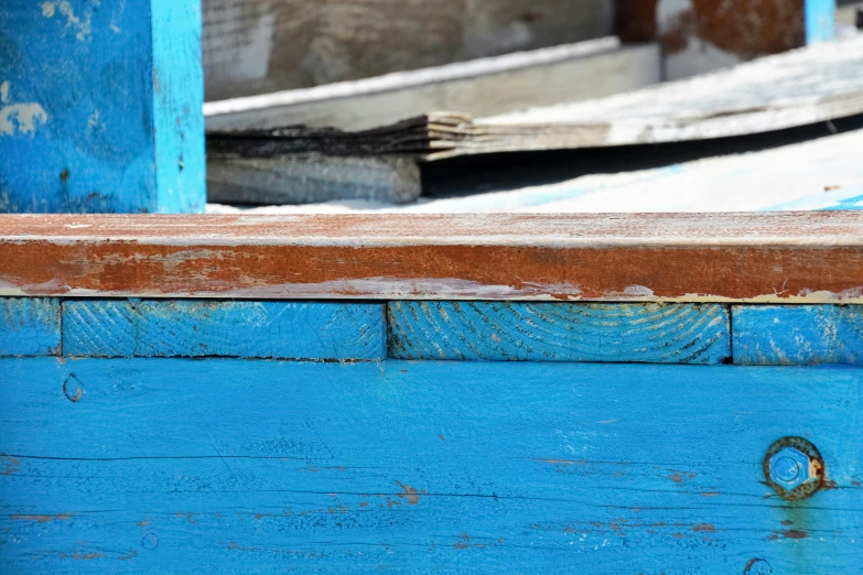 the blue paint on the old wooden bench is chipped