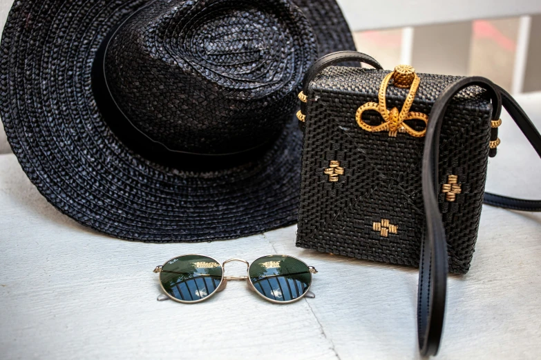 a straw hat and sunglasses next to a small suitcase