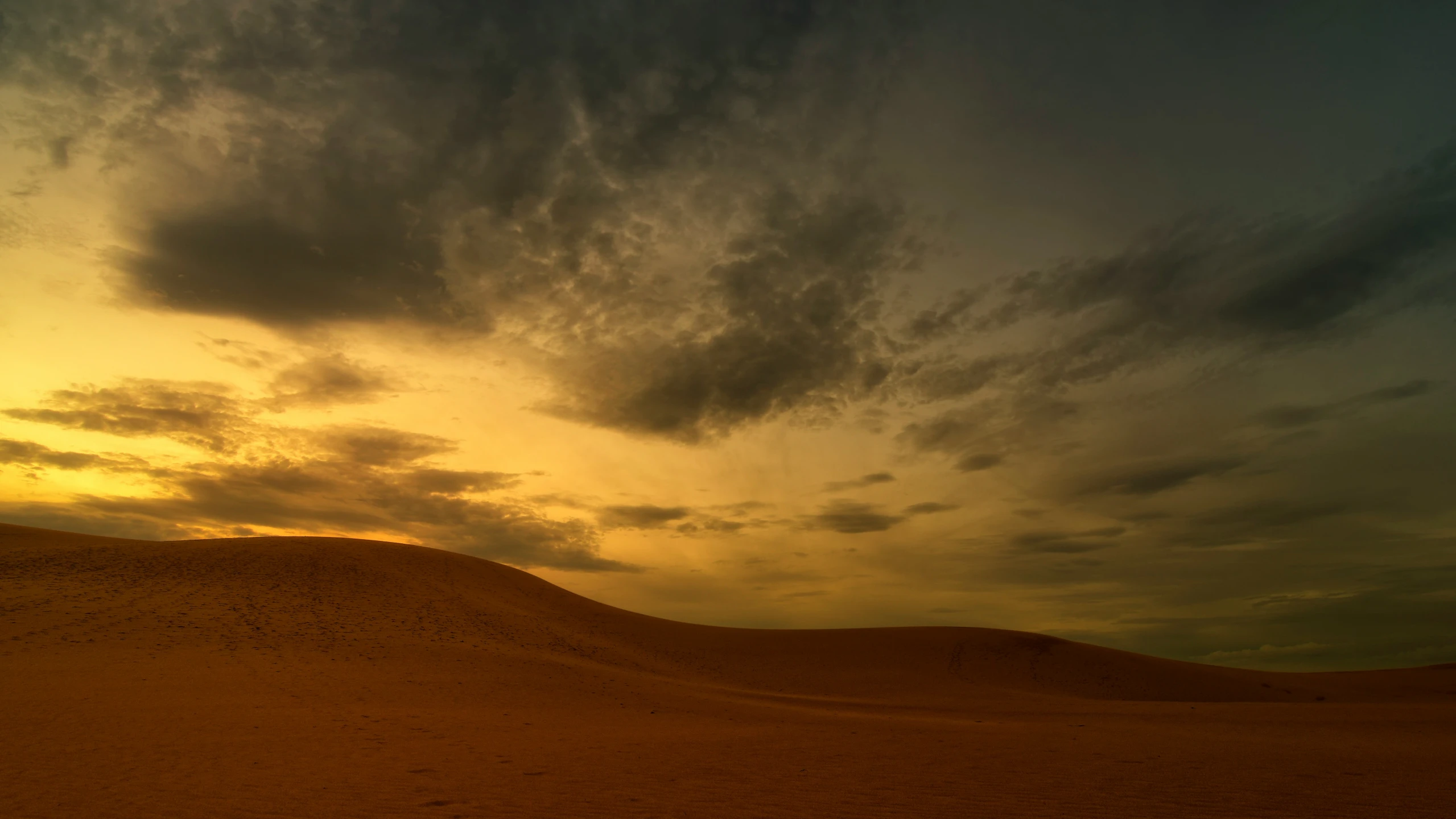 the sky is orange and cloudy over a desert