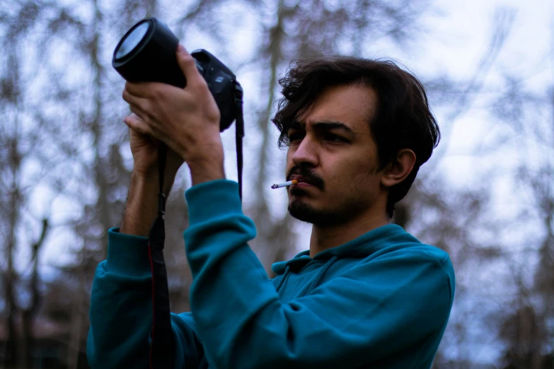 man in a hoodie holding a camera up to the sky