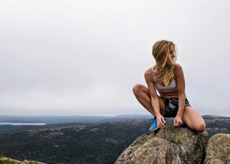 a woman is sitting on top of a rock