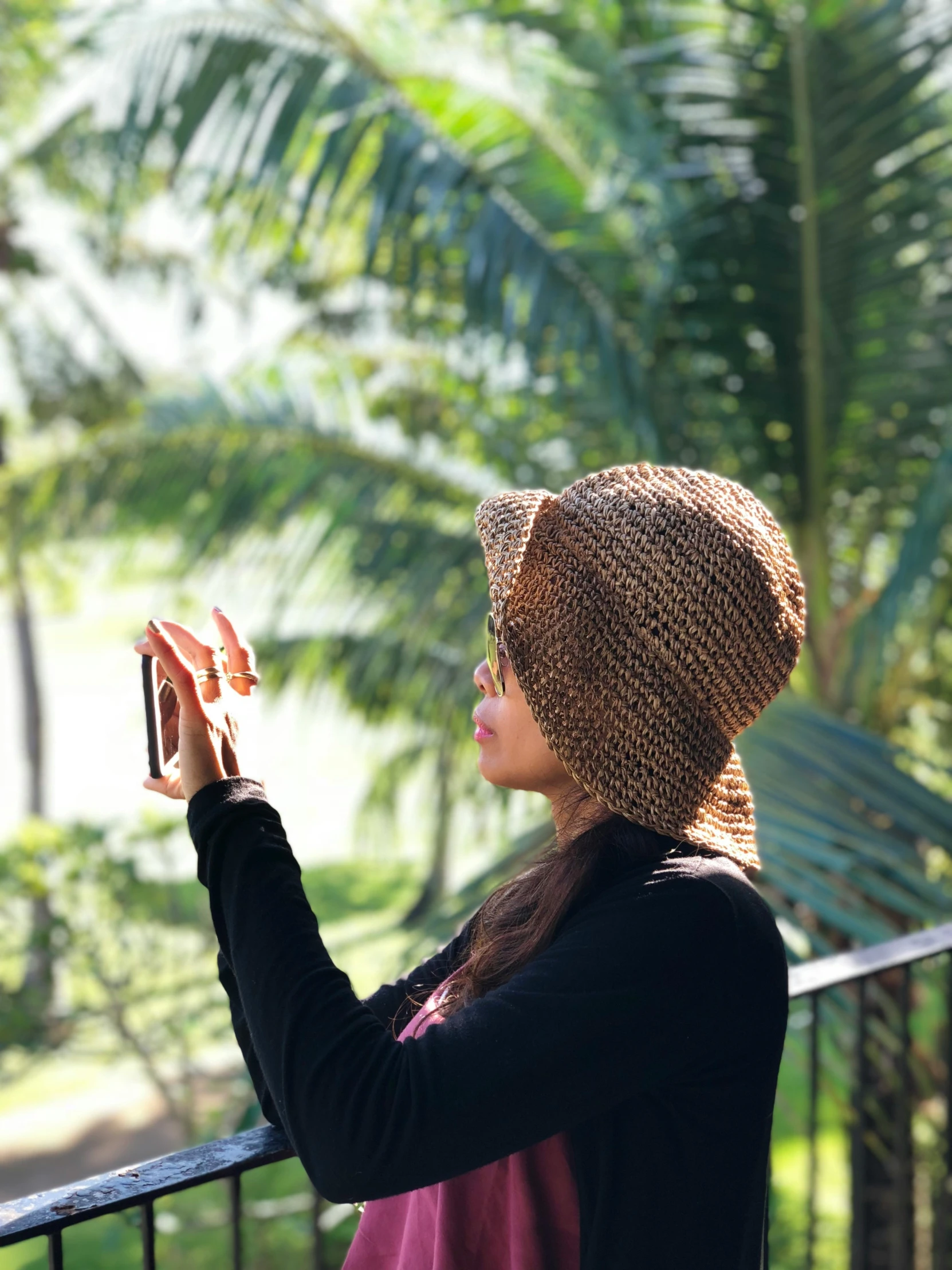 a woman standing next to a fence looking at her phone