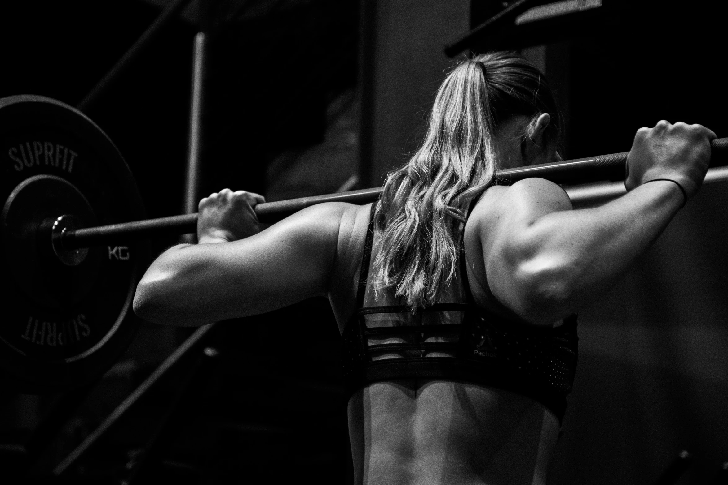 a woman that is holding a barbell in her hand