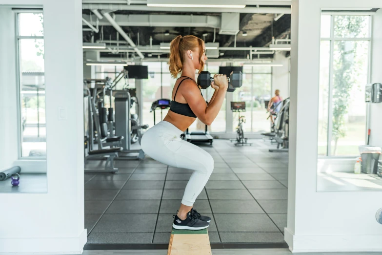 a woman is performing squats in a gym