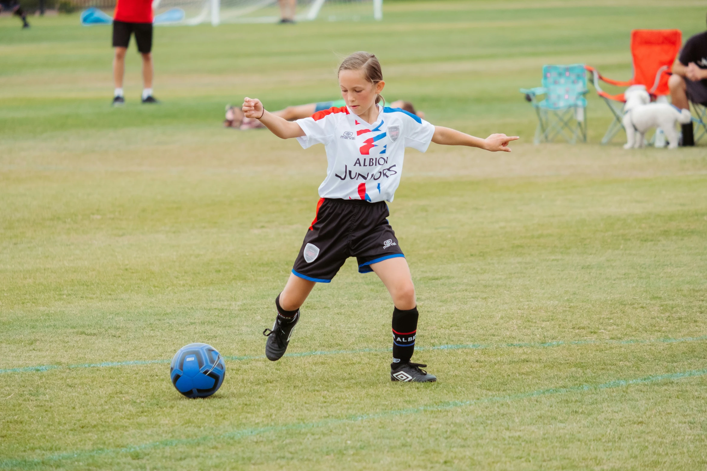 a little girl standing in front of a blue soccer ball