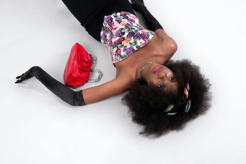 a black woman with afro hair and a dress laying on her side on the floor