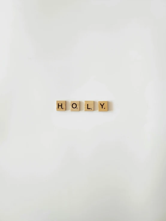 scrabble font spelling out the word holly on a white wall