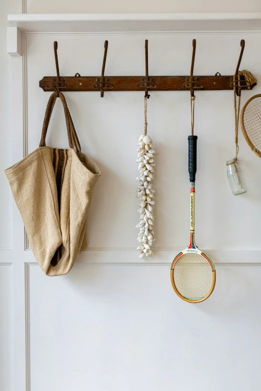 a wall rack with two tennis racquets and a ball hanging on a coat hook