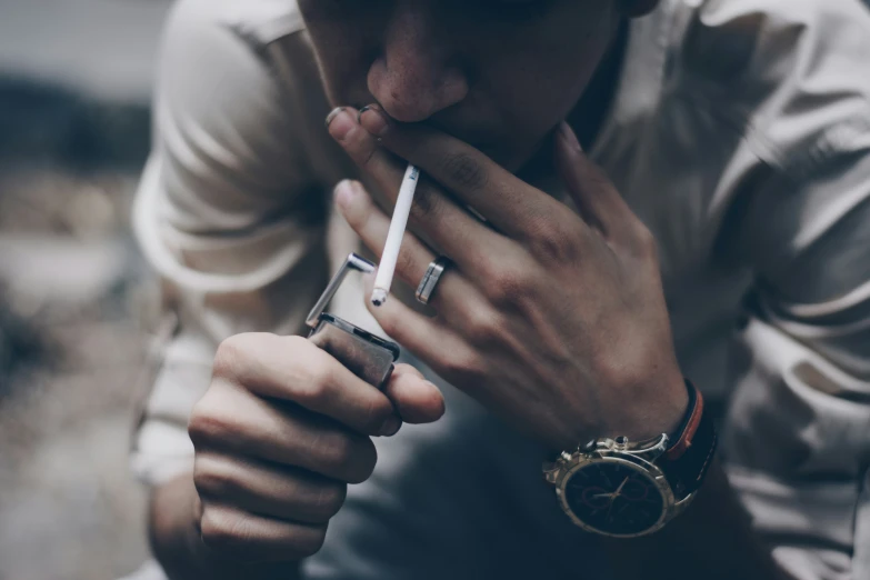 man with a watch on his wrist holding cigarettes