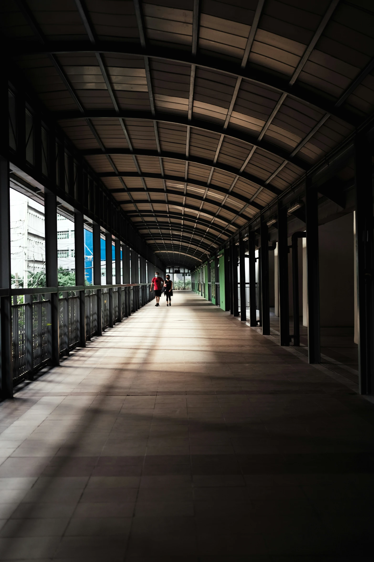 some people walk down the sidewalk in a parking garage