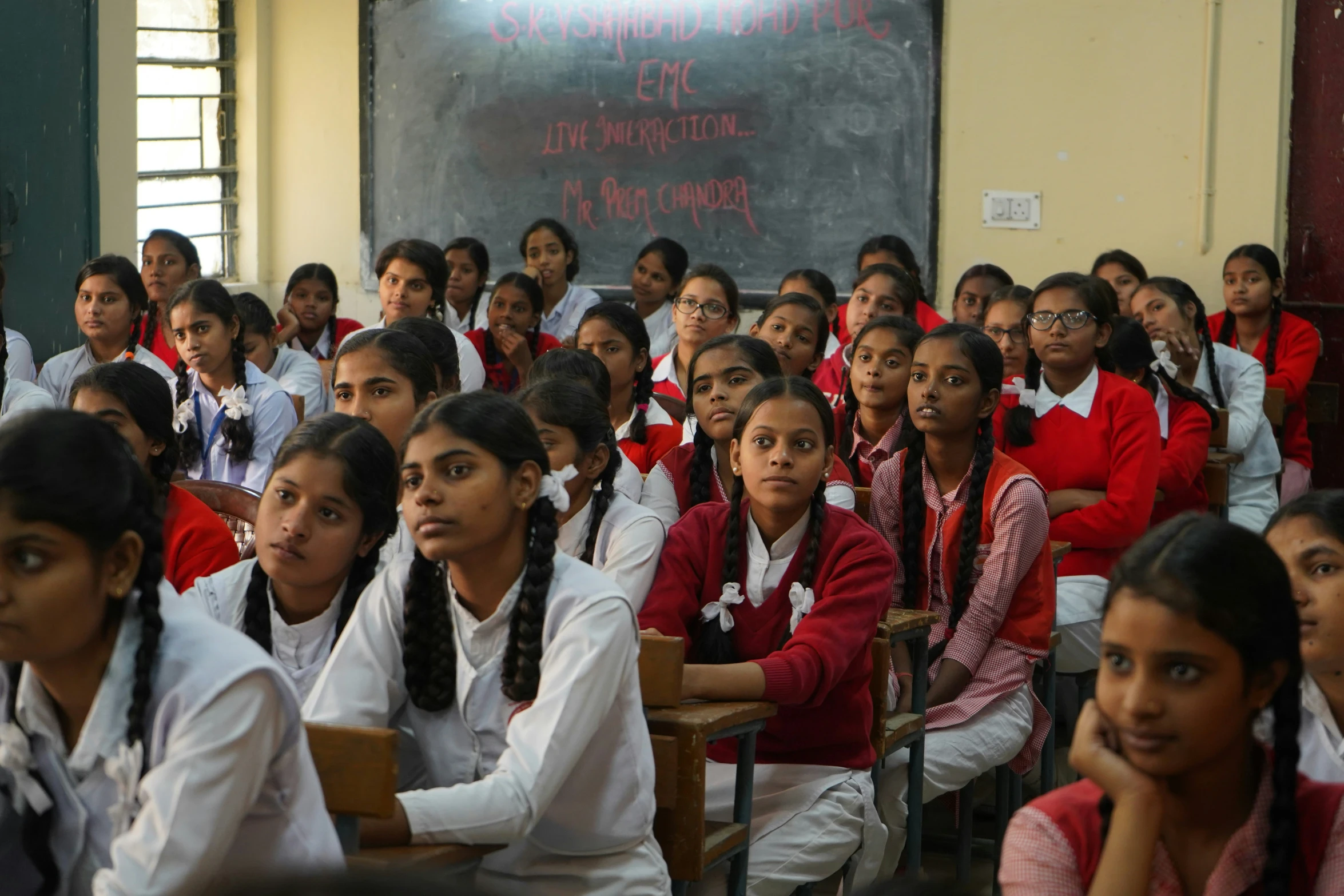 many girls wearing red and white uniforms sitting in chairs