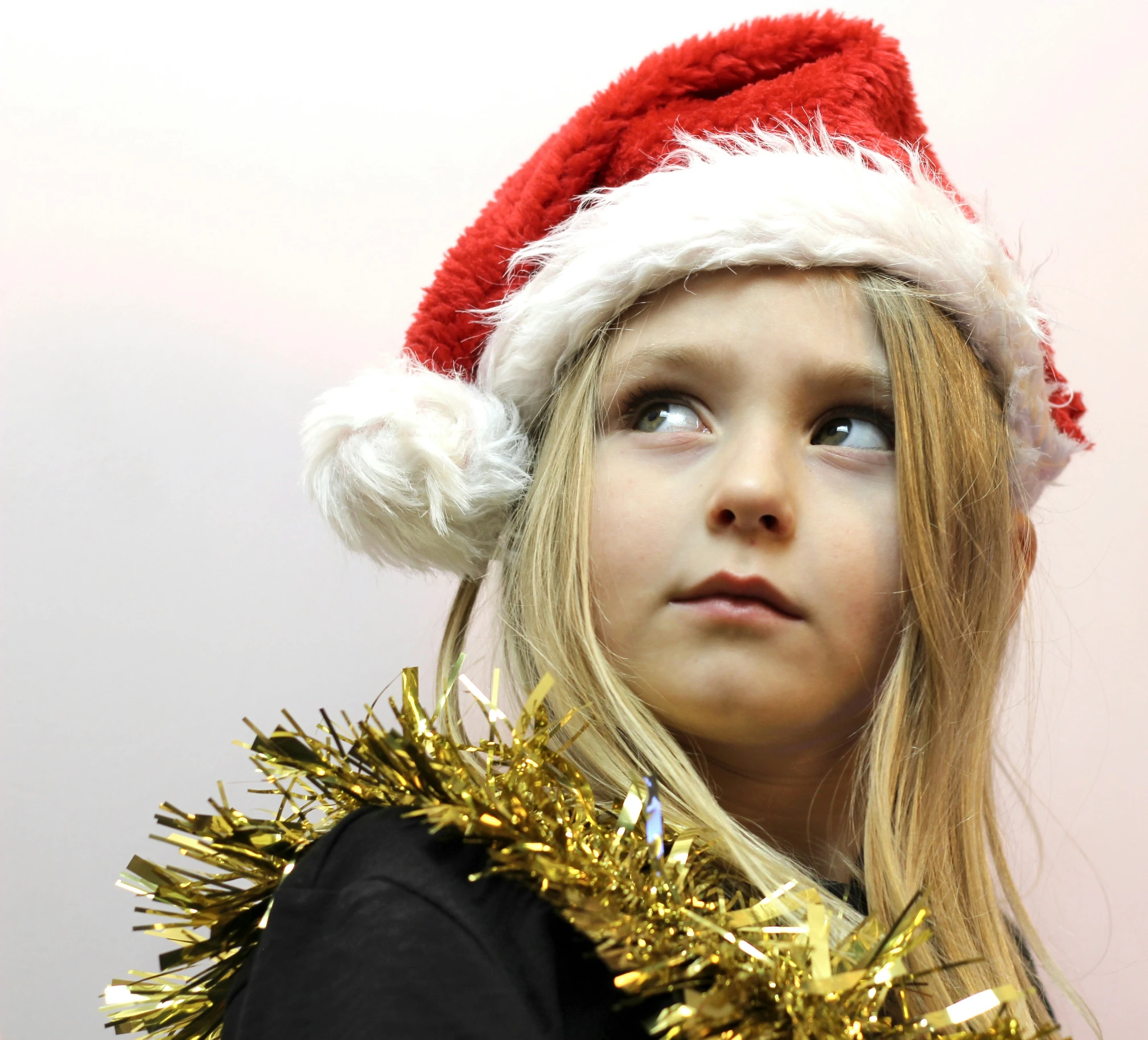 little girl wearing a santa hat and tinsels