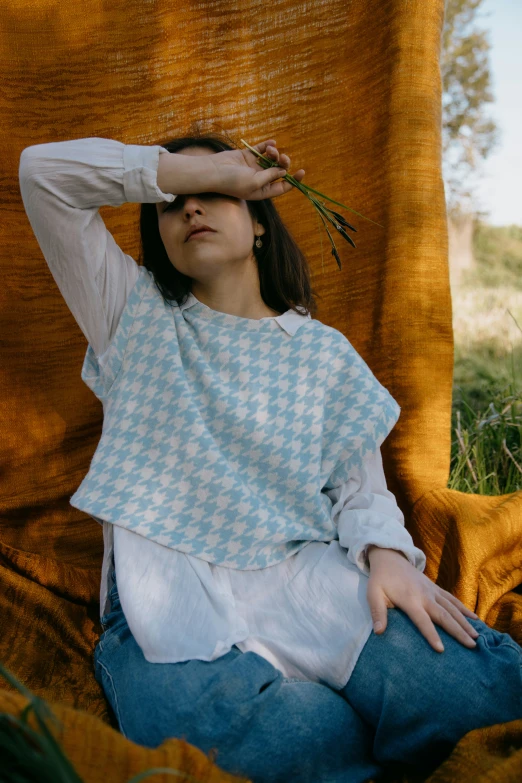 a girl that is sitting down with a plant in her hand