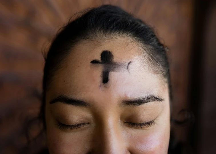 a girl is putting a cross on her head