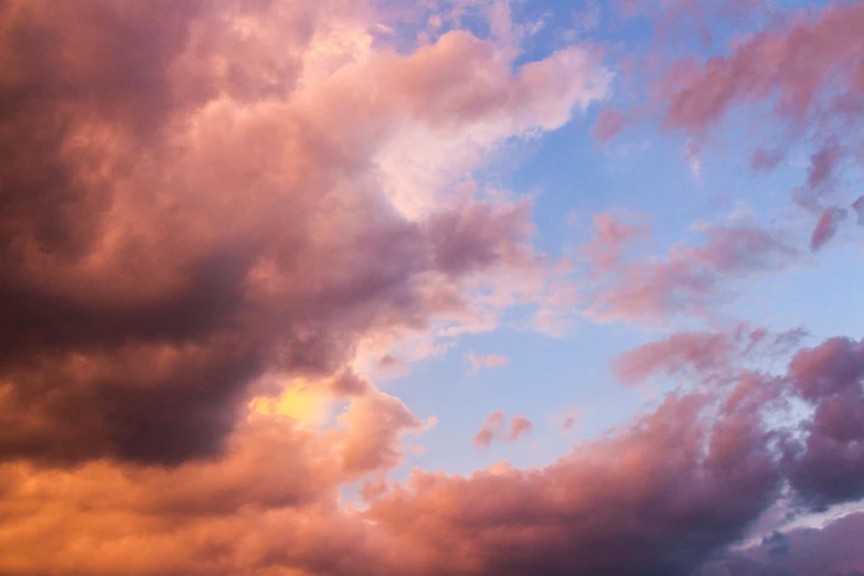 a plane flying through a cloudy blue sky