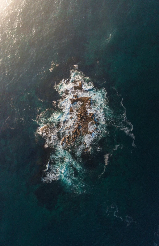 an aerial s of the ocean with some small rocks