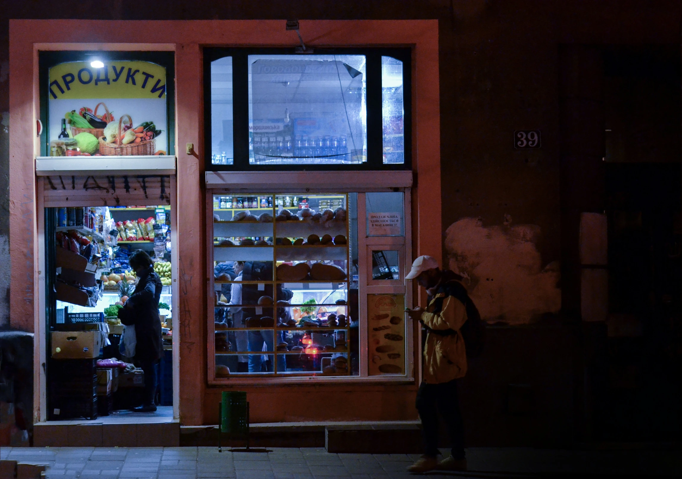 two people stand outside the shop at night