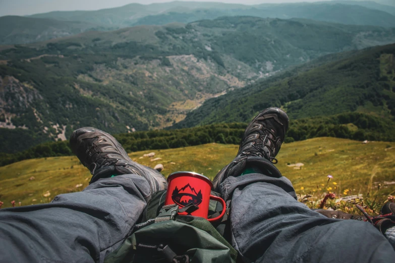 a man with his feet in the air, overlooking a mountain valley