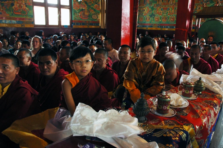 buddhist people are sitting in the middle of a room with a big table