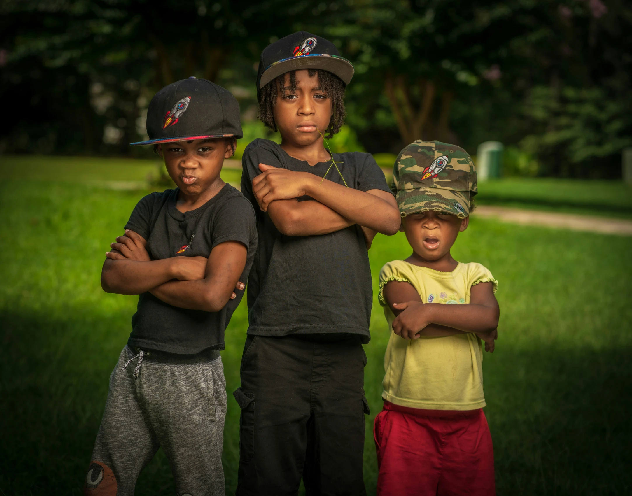 three children standing together in a park posing