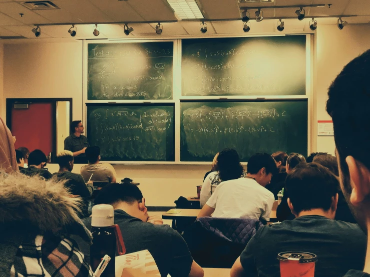 a classroom with a lot of students sitting and doing soing