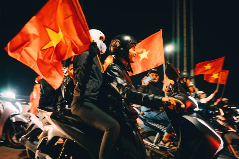 a group of people riding motorcycles holding flags