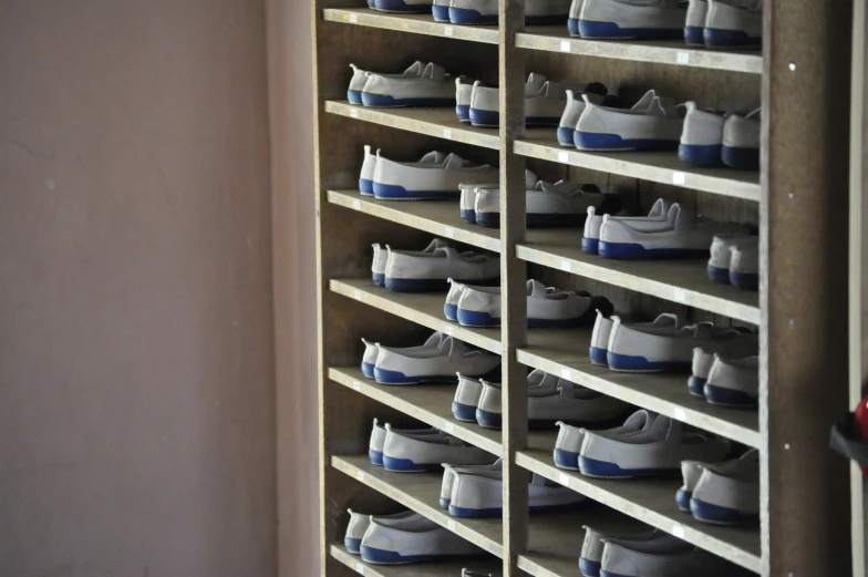 white and blue sneakers sit on shelves against a wall