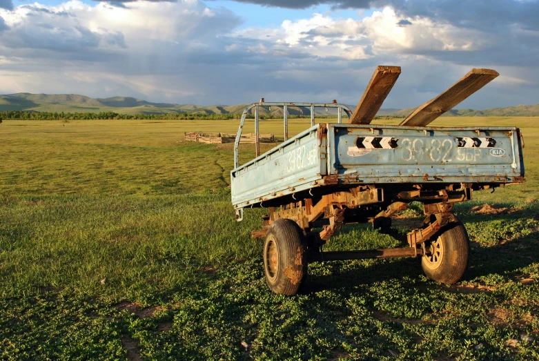 an old blue metal work truck in grassy field