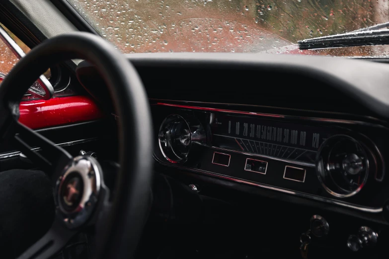 an old car dashboard with raindrops falling down on it