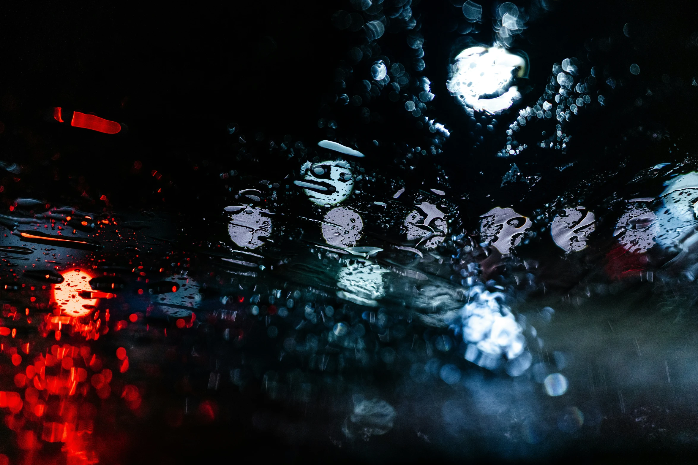 a dark image of cars driving on a rainy night