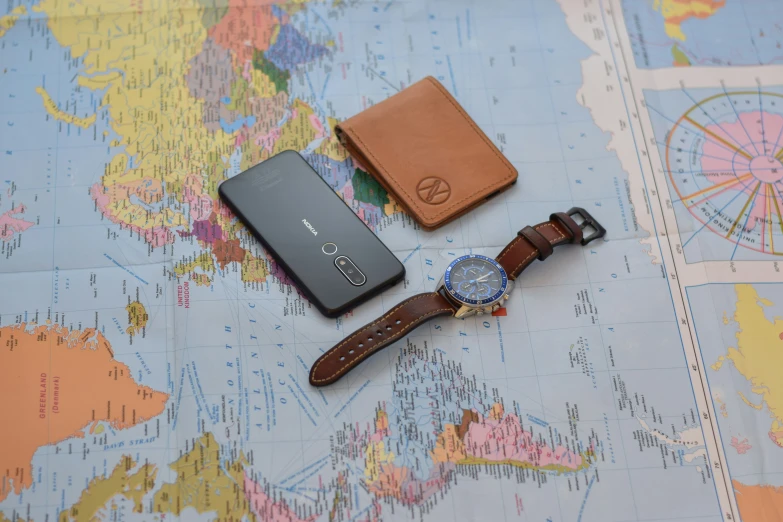 a small notebook with a watch and passport on a map