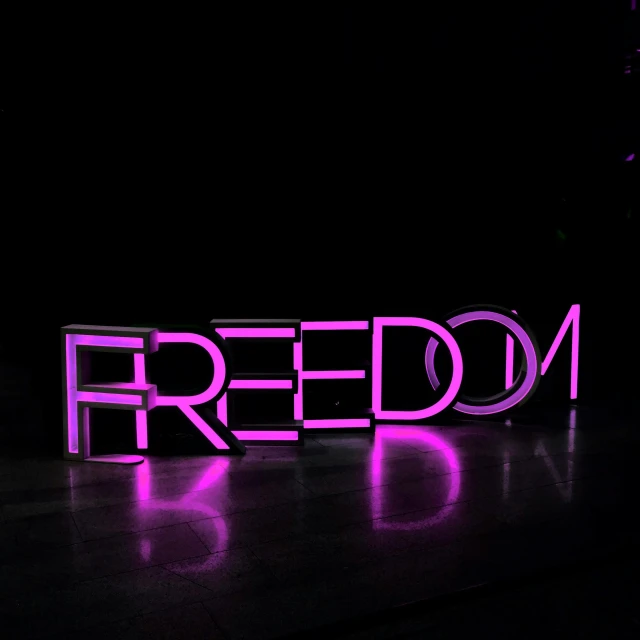the word'freedom'lit up in purple, sitting on a black surface
