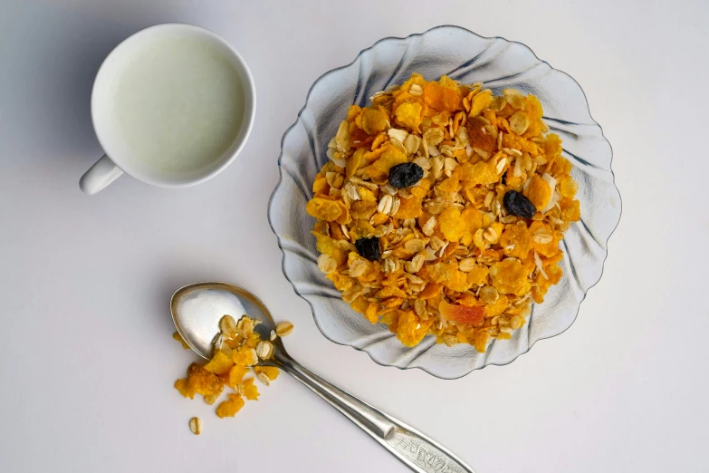 a bowl of cereal, spoon and a cup