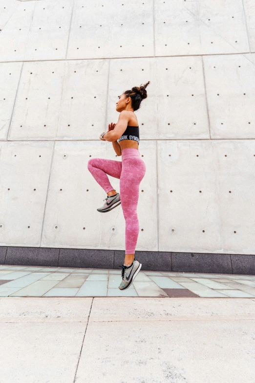 a woman standing on her hind legs wearing pink tight pants