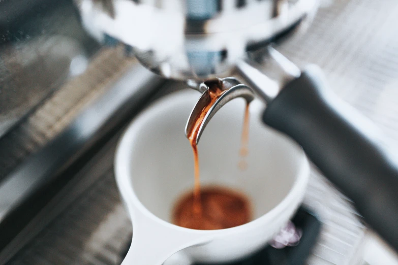 a spoon pouring some caramel into a cup