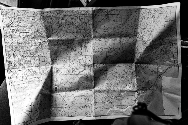 this is a black and white po of a hand holding up a map