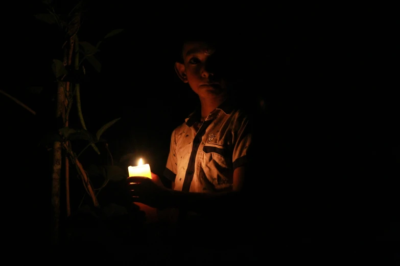 a young man holding a lit candle in his hand