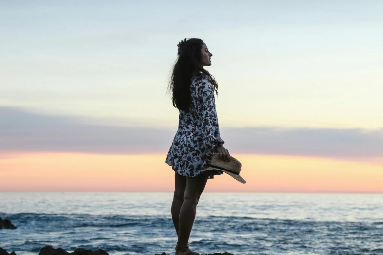 a woman standing on top of rocks near the ocean