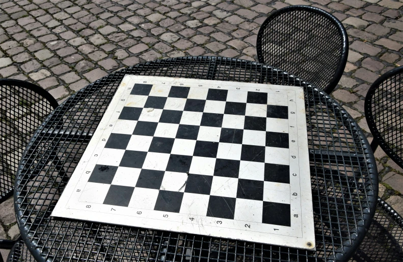 a chess board laying on top of a metal bench