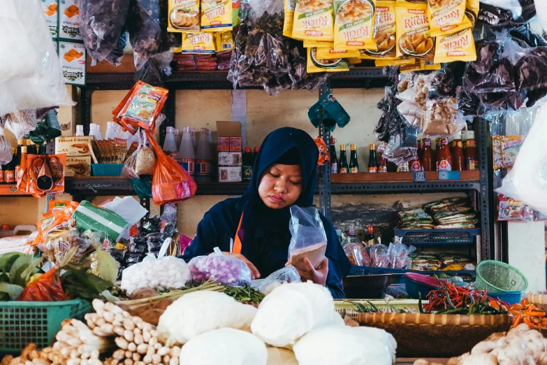 a woman is reading a book in a market