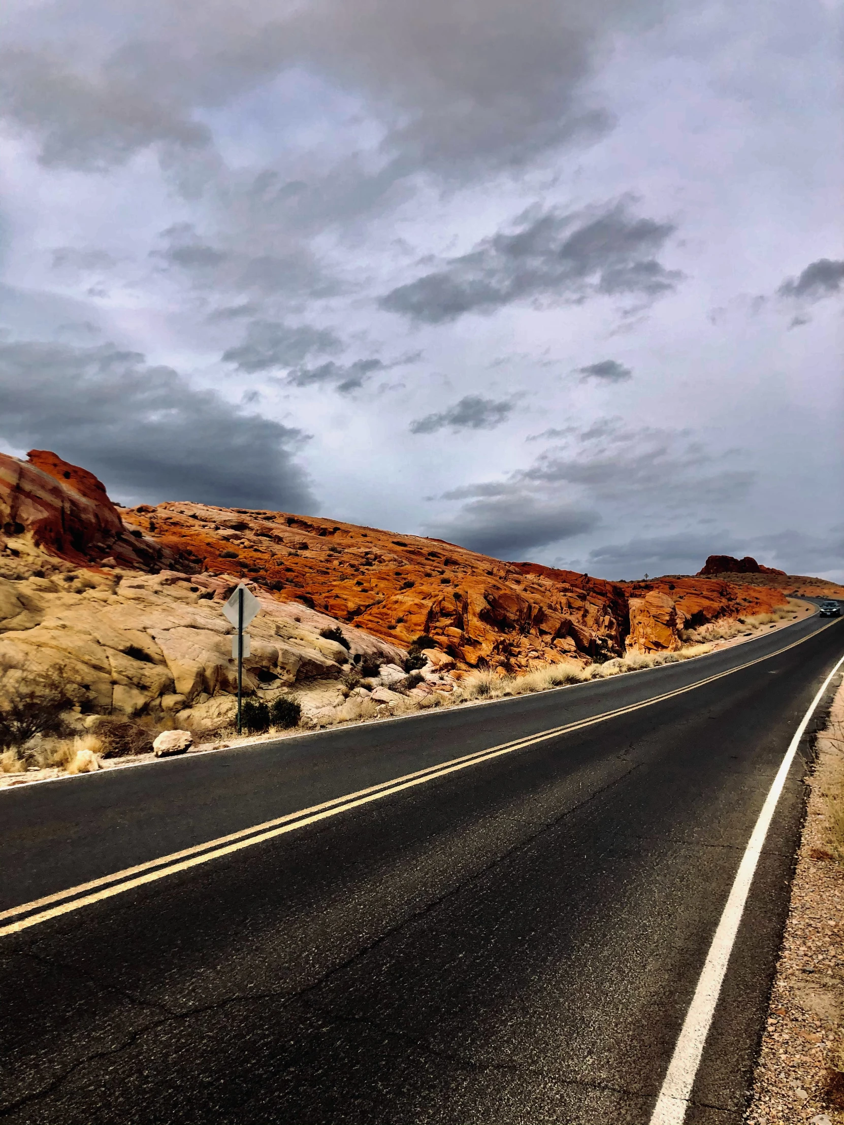 a car is driving on the road that runs past some cliffs