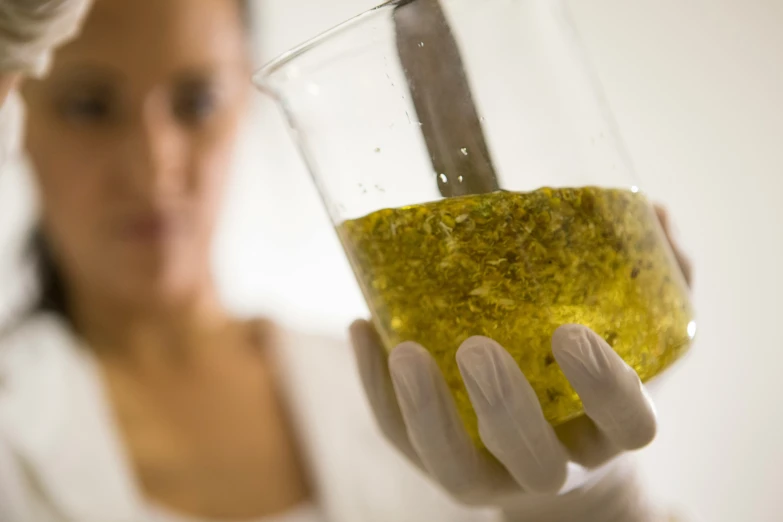 woman holding glass with olive oil in it, ready to drink